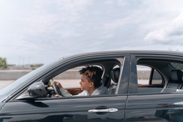 Mastering the First Impression: Your intriguing post title goes here Side view of a young male teenager focused on driving a car in bright daylight.